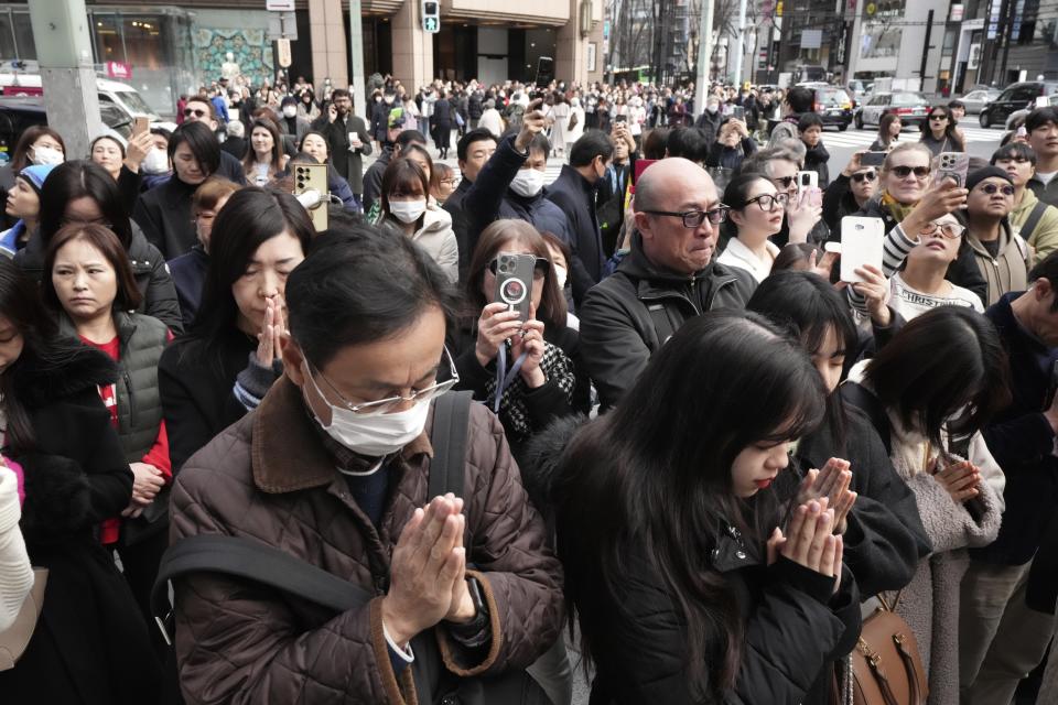 Bystanders pray when an annual tribute started at 2:46 p.m. for the victims of a 2011 disaster Monday, March 11, 2024, in Tokyo. Japan on Monday marked the 13th anniversary of the massive earthquake, tsunami and nuclear disaster that struck Japan's northeastern coast. (AP Photo/Eugene Hoshiko)