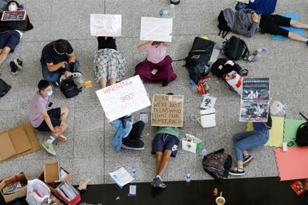 Anti-government demonstrators sit in a designated area of the arrival hall of the airport in Hong Kong after police and protesters clashed the previous night