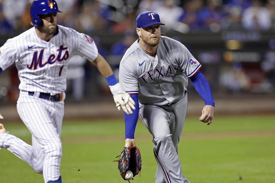 Texas Rangers pitcher Will Smith flips the ball to first past New York Mets' Jeff McNeil for the out during the eighth inning of a baseball game Tuesday, Aug. 29, 2023, in New York. (AP Photo/Adam Hunger)