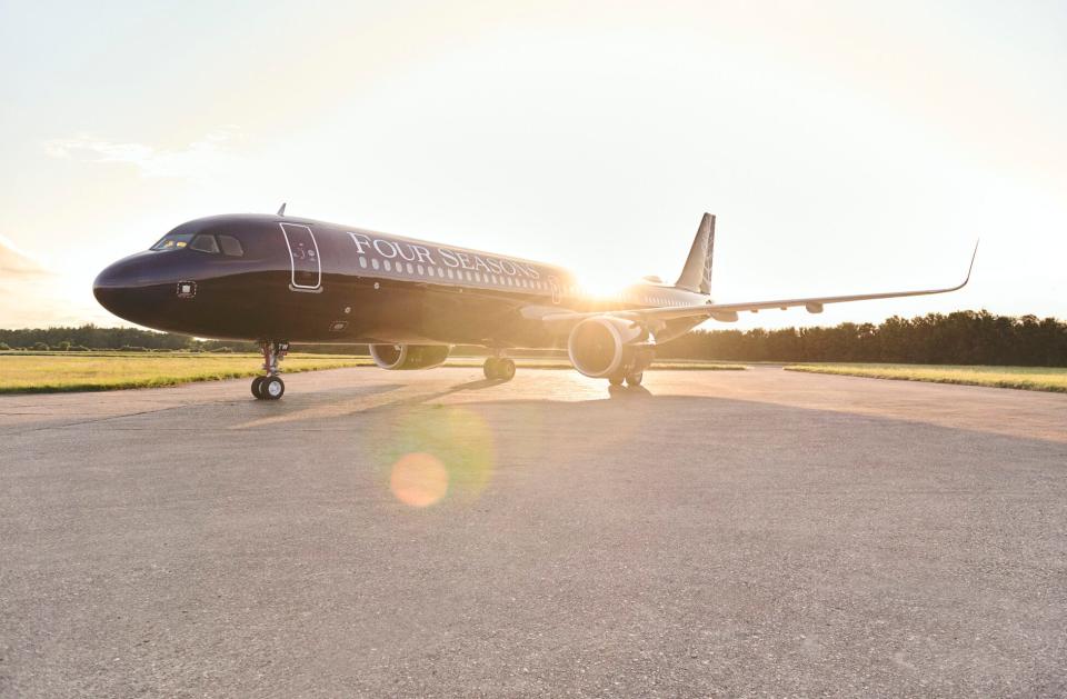 An Airbus A321LR owned by Four Seasons in its purple livery as the sunsets behind the jet