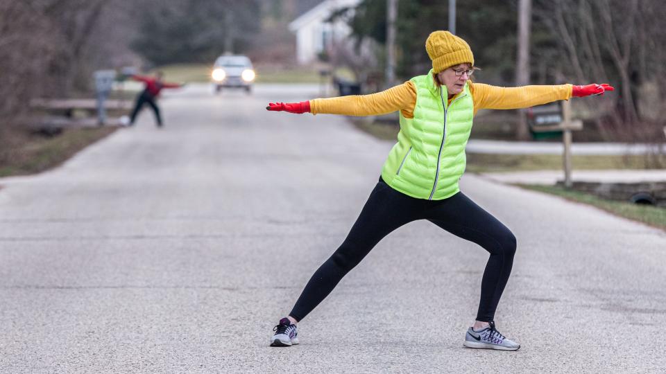 Maureen Lewis leads an outdoor morning exercise routine for neighbors on her street in Menomonee Falls, Wisconsin, on March 27. Lewis stands in the street to allow participants to see her from their driveways while observing social distancing. The workout includes light stretches and exercises for 10 to 15 minutes.