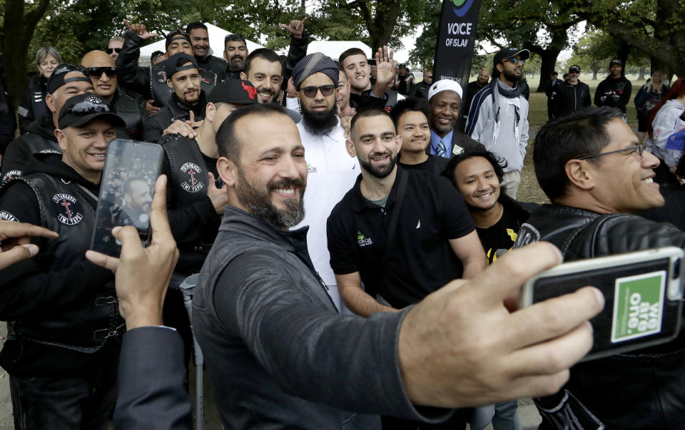 Survivor of the Al Noor mosque shootings, Temel Atacocugu, center, takes a selfie with members of the Tu Tangata motorcycle club outside the mosque in Christchurch, New Zealand, Sunday, March 15, 2020. A national memorial in New Zealand to commemorate the 51 people who were killed when a gunman attacked two mosques one year ago has been canceled due to fears over the new coronavirus. (AP Photo/Mark Baker)