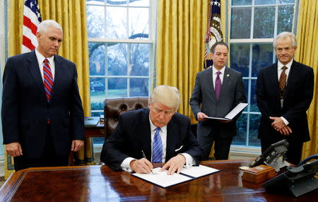 FILE PHOTO: U.S. President Donald Trump signs the executive order for the reinstatement of the Mexico City Policy in the Oval Office of the White House in Washington January 23, 2017. With Trump (L-R) are Vice President Mike Pence, White House Chief of Staff Reince Priebus and head of the White House Trade Council Peter Navarro. REUTERS/Kevin Lamarque/File Photo