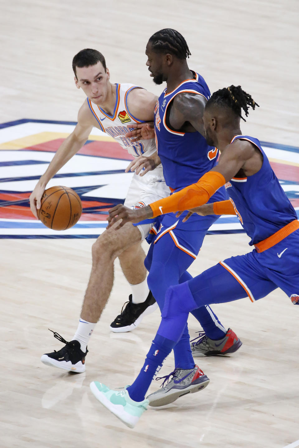 Oklahoma City Thunder forward Aleksej Pokusevski (17) goes against New York Knicks forward Julius Randle (30) and center Nerlens Noel (3) during the first half of an NBA basketball game, Saturday, March 13, 2021, in Oklahoma City. (AP Photo/Garett Fisbeck)