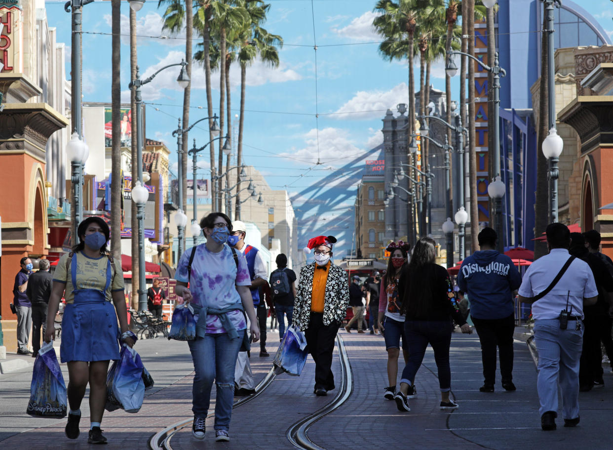 ANAHEIM, CA - NOVEMBER 19: Masked visitors walk along Hollywood Land at Disney California Adventure which opened on Thursday, Nov. 19, 2020 in Anaheim, CA but without rides. There were plenty of dining and shopping opportunities. (Myung J. Chun / Los Angeles Times via Getty Images)