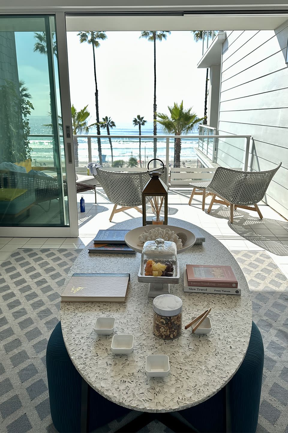 a table with a glass top and a glass window with a view of the ocean and trees