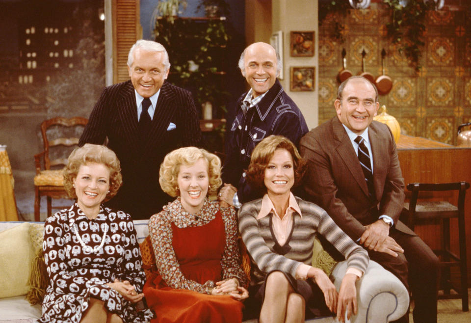 The cast poses on or behind a couch for a publicity portrait on the set of the CBS situation comedy 'Mary Tyler Moore,' Studio City, Los Angeles, California, November 21, 1975. Those pictured are (left to right) Betty White, as Sue Ann Nivens, Ted Knight (1923 - 1986), as Ted Baxter, Georgia Engel, as Georgette Franklin Baxter, Gavin McLeod, as Murray Slaughter, Mary Tyler Moore, as Mary Richards, and Ed Asner, as Lou Grant. (Photo by CBS Photo Archive/Getty Images)