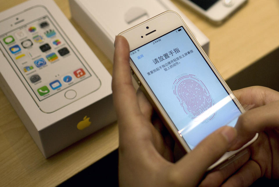 FILE - In this Sept. 20, 2013 file photo, a customer configures the fingerprint scanner technology built into iPhone 5S at an Apple store in Beijing. Samsung’s new Galaxy S5 smartphone is more durable than last year’s model and other leading Android phones, but the iPhone 5s outperformed all of them in part because of its smaller size, a new study finds. (AP Photo/Andy Wong, File)