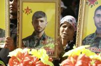 Mourners hold portraits of fighters from the Kurdish People's Protection Units' (YPG), killed in combat against Islamic State (IS) group jihadists