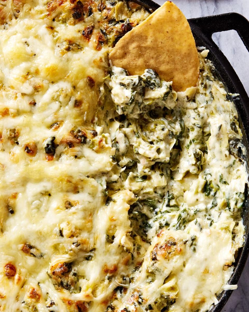 spinach artichoke dip in a cast iron skillet served with tortilla chips