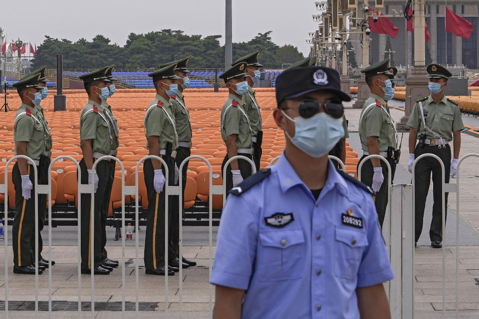 A police officer wearing a face mask to help curb the spread of the coronavirus stands guard near masked Chinese paramilitary officers preparing for their duties near rows of seats setup on Tiananmen Square in Beijing, Monday, June 28, 2021. China is marking the centenary of its ruling Communist Party this week by heralding what it says is its growing influence abroad, along with success in battling corruption at home. (AP Photo/Andy Wong)