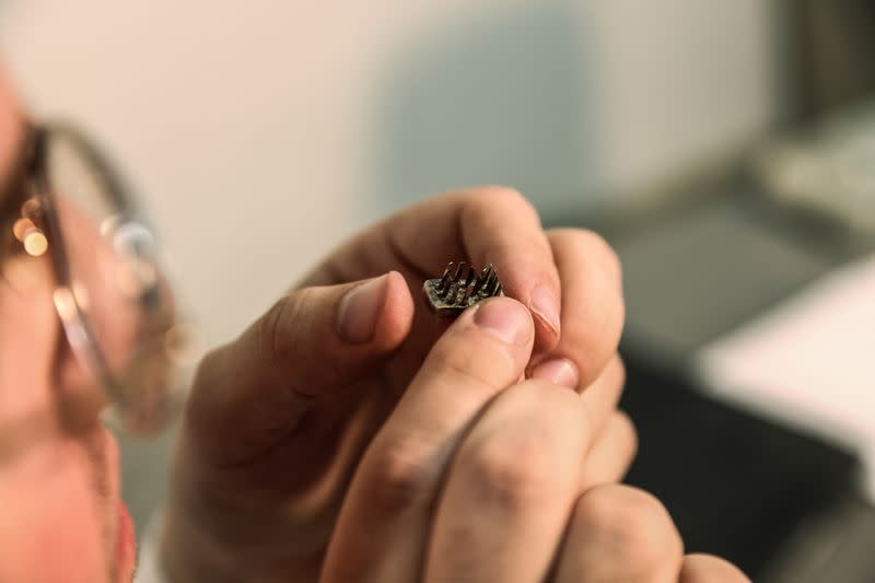 A worker at an Israeli auction house holds a die from a tattoo kit, which they say were used on inmates at Auschwitz death camp, in Gilo