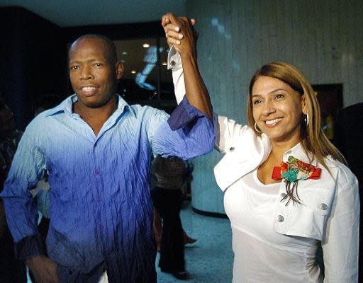 El ex jugador de la seleccion de futbol de Colombia Faustino Asprilla (I) y la congresista Rocío Arias, levantan sus brazos tras anunciar en rueda de prensa su intencion de candidatarse para Camara de Representantes, el 19 de enero de 2006 en Cali (AFP/Archivos | Str)