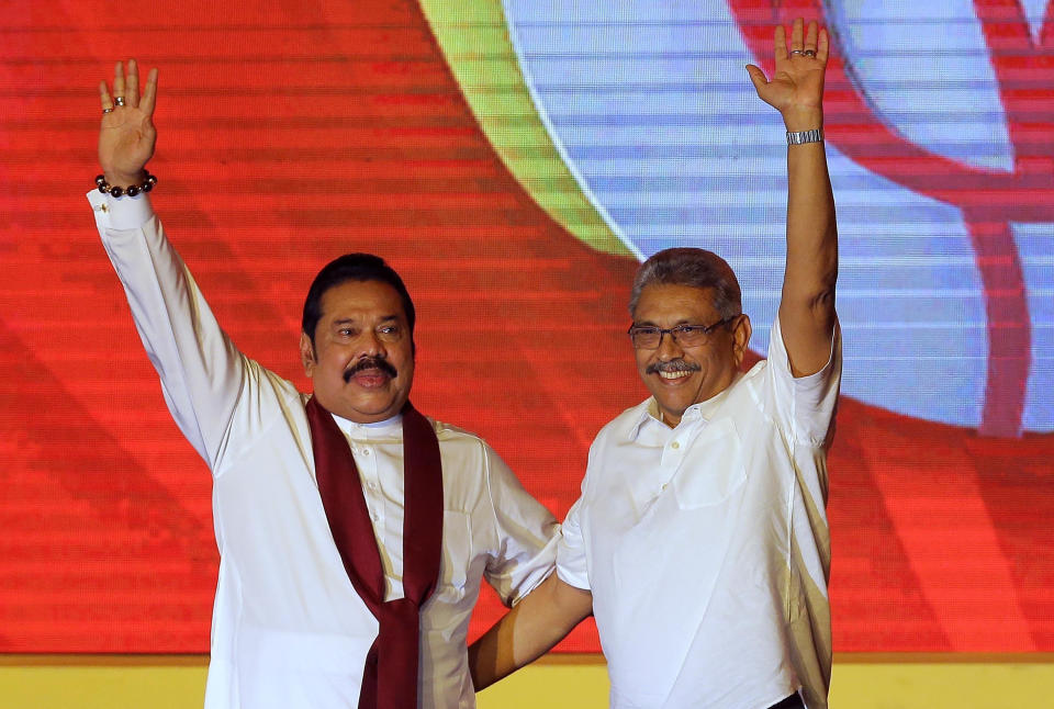 FILE - In this Aug. 11, 2019, file photo, former Sri Lankan President Mahinda Rajapaksa, left, and his brother and former Defense Secretary Gotabaya Rajapaksa wave to supporters during a party convention held to announce the presidential candidacy in Colombo, Sri Lanka. Rajapaksa is credited with helping end the country’s long civil war and is revered as a hero by the Sinhalese Buddhist majority. He comfortably won Saturday’s presidential election with about 52% of the ballots. But minorities largely voted for his opponent, fearing Rajapaksa because of allegations of wartime human rights violations against him. (AP Photo/Eranga Jayawardena, File)