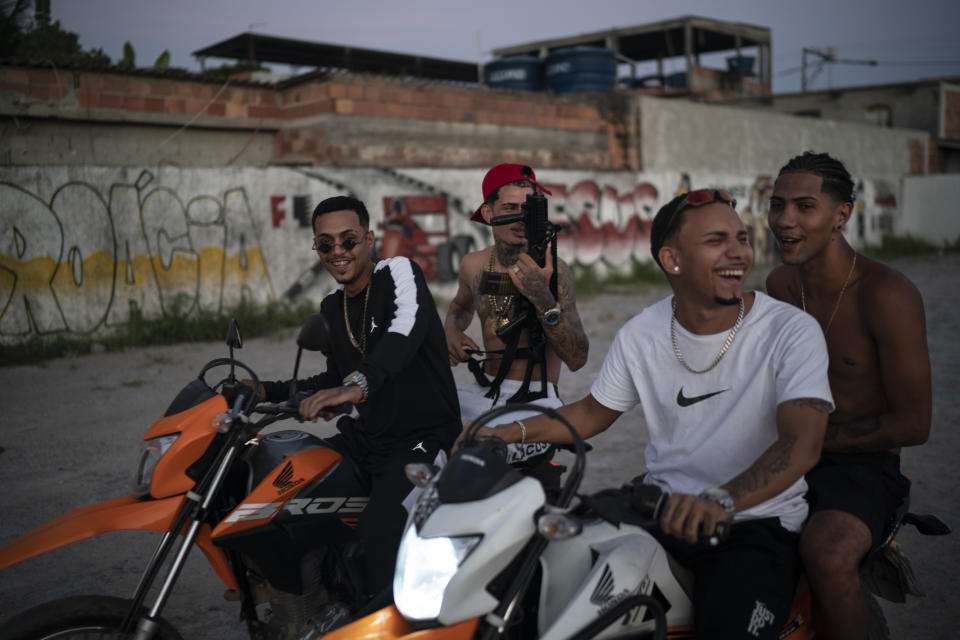 Trap de Cria artists Marcos Borges, known as "MbNaVoz," from left, Wesley Souza "MC Branquinho," Fernando "Barbeirin" and Pablo "PBSant" ride motorcycles holding an Airsoft gun as they record a music video for the song "Se Tem Glock" in the Jardim Catarina community in Sao Gonçalo, Rio de Janeiro state, Brazil, Sunday, April 11, 2021. Trap de Cria, roughly translated into Homegrown Trap, recently stemmed from Atlanta-style trap in Rio’s favelas and remains largely unknown outside them. (AP Photo/Felipe Dana)