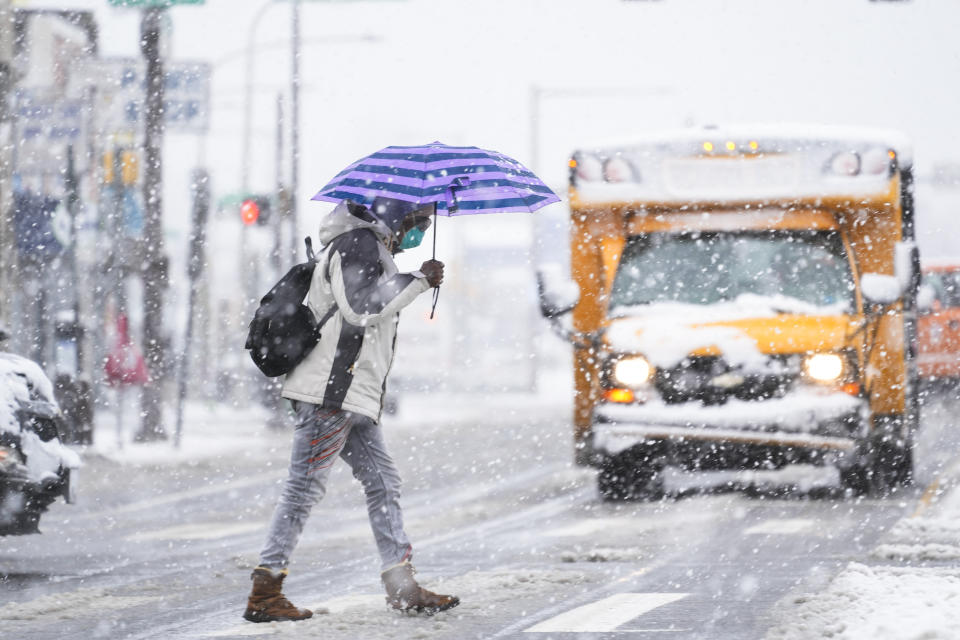 A person crosses a street during a winter snow storm in Philadelphia, Tuesday, Feb. 13, 2024. Parts of the Northeast were hit Tuesday by a snowstorm that canceled flights and schools and prompted warnings for people to stay off the roads, while some areas that anticipated heavy snow were getting less than that as the weather pattern changed. (AP Photo/Matt Rourke)