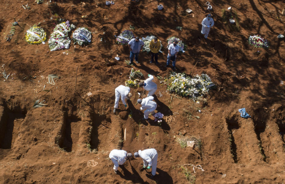 FILE - In this May 20, 2020, file photo, cemetery workers in protective clothing bury a COVID-19 victim at the Vila Formosa cemetery in Sao Paulo, Brazil. Even amid a global pandemic, there’s no sign that corruption is slowing down in Latin America. In Brazil, which has the world's second-highest number of confirmed cases, police created a task force to investigate crimes tied to the pandemic. (AP Photo/Andre Penner)