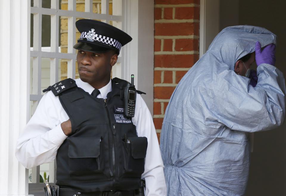 A forensics officer (R) passes a policeman to enter a house where the bodies of three children were found, in New Malden, southwest London April 23, 2014. A 43-year-old woman has been arrested on suspicion on murder after the bodies of three children were found at a house in southwest London, police said on Wednesday. Police said a four-year-old girl and two boys, both aged three, were found dead at a residential address in New Malden on Tuesday evening. REUTERS/Olivia Harris (BRITAIN - Tags: CRIME LAW SOCIETY)