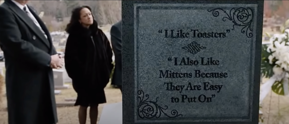 A tombstone reading "I like toasters. I also like mittens because they're easy to put on"