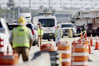 Construction workers walk from the scene in the westbound lanes of I-275 near Gandy Boulevard on Friday, Sep 23, 2022, in St. Petersburg, Fla., where Deputy Michael Hartwick, 51, was hit and killed overnight. Michael Hartwick, a Florida sheriff's deputy working an overnight shift to provide safety at a construction zone was struck and killed by a worker operating a front end loader, officials said.(Douglas R. Clifford/Tampa Bay Times via AP)