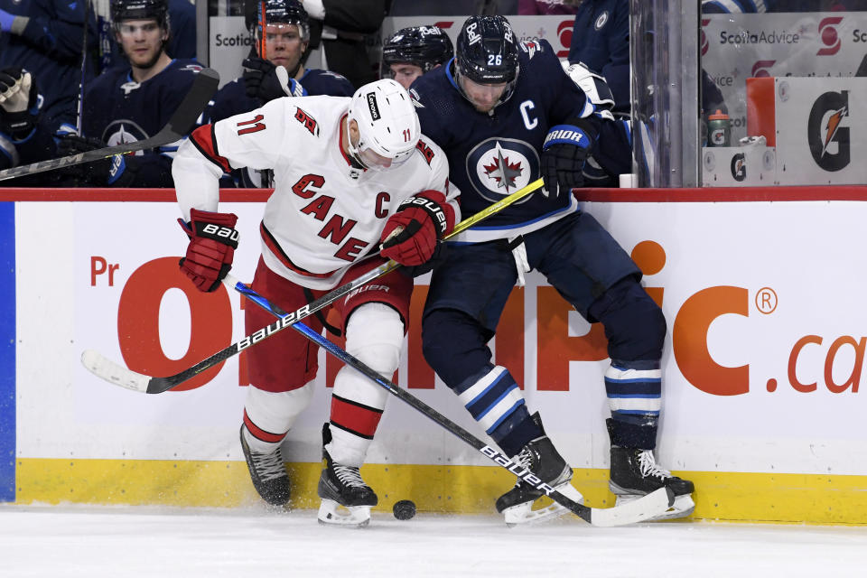 Winnipeg Jets' Blake Wheeler (26) and Carolina Hurricanes' Jordan Staal (11) battle for the puck during the second period of an NHL game in Winnipeg, Manitoba, Tuesday, Dec. 7, 2021. (Fred Greenslade/The Canadian Press via AP)