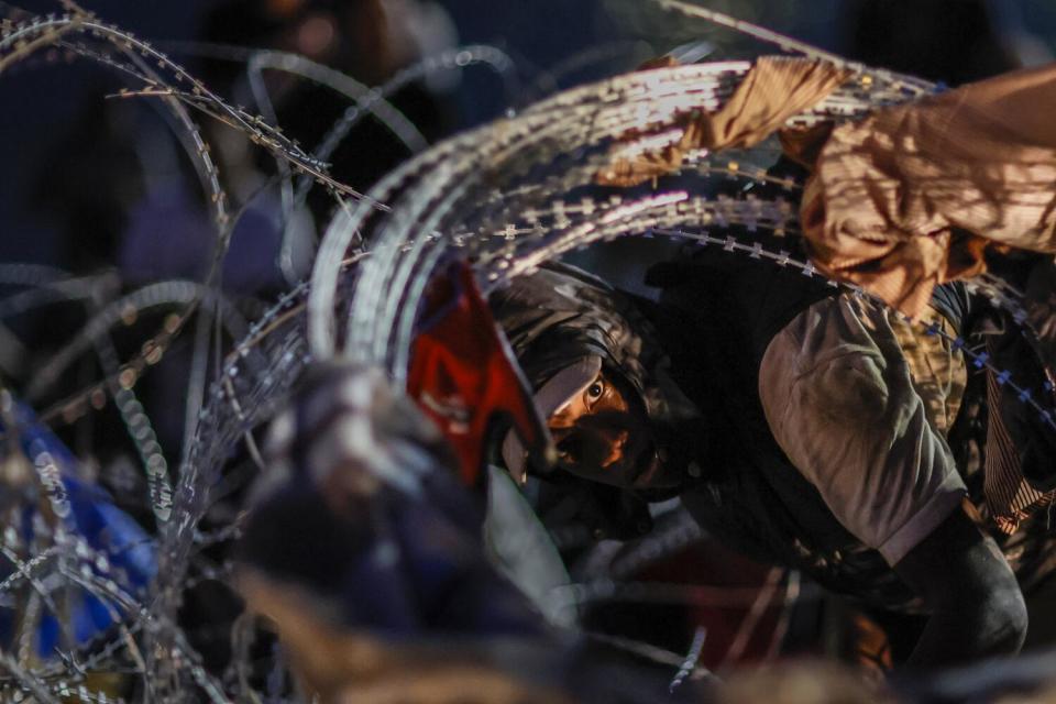 A man crawls through razor wire.