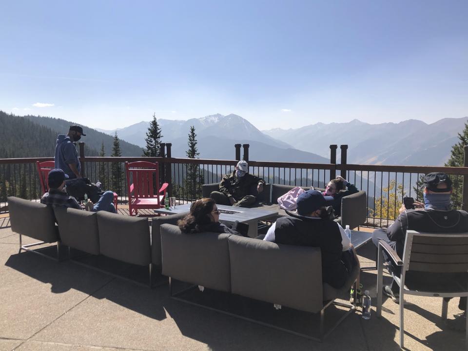 In this Oct. 3, 2020 photo, people gather in outdoor seats at the top of Aspen Mountain in Aspen, Colo. Aspen has not seen much of a drop-off in visitors during the coronavirus pandemic because of its numerous precautions in town and multitude of outdoor activities. (AP Photo/John Marshall)