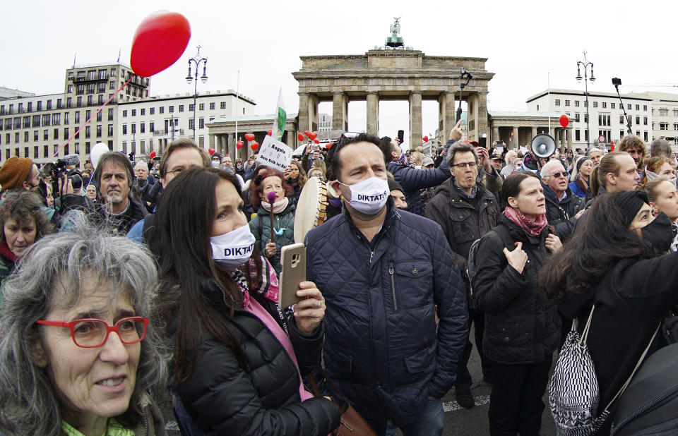 People attend a protest rally in front of the Brandenburg Gate in Berlin, Germany, Wednesday, Nov. 18, 2020 against the coronavirus restrictions in Germany. Police in Berlin have requested thousands of reinforcements from other parts of Germany to cope with planned protests by people opposed to coronavirus restrictions. Word on the mask reads 'Dictatorship'. (AP Photo/Michael Sohn)