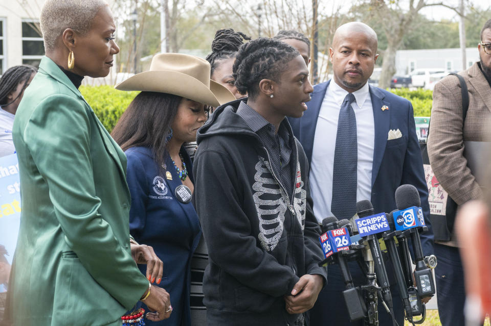 Darryl George, center, makes a comment during a press conference before a hearing regarding George's punishment for violating school dress code policy because of his hair style, Thursday Feb. 22, 2024 at the Chambers County Courthouse in Anahuac, Texas. A judge has ruled that George's monthslong punishment by his Texas school district for refusing to change his hairstyle does not violate a new state law prohibiting race-based hair discrimination. (Kirk Sides/Houston Chronicle via AP)