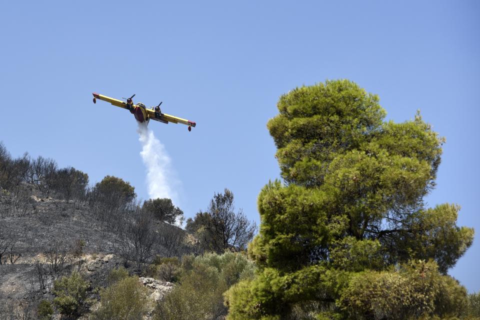 An aircraft drops water in Lampiri village, east of Patras city, Greece, Sunday, Aug. 1, 2021. A wildfire that broke out Saturday in western Greece forced the evacuation of four villages and people on a beach by the Fire Service, the Coast Guard and private boats, authorities said. (AP Photo/Andreas Alexopoulos)