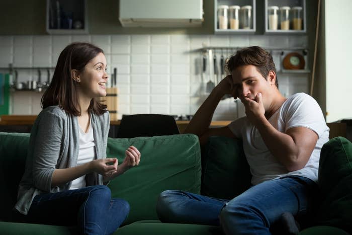 Two people having a conversation on a sofa, one appears to be consoling the other