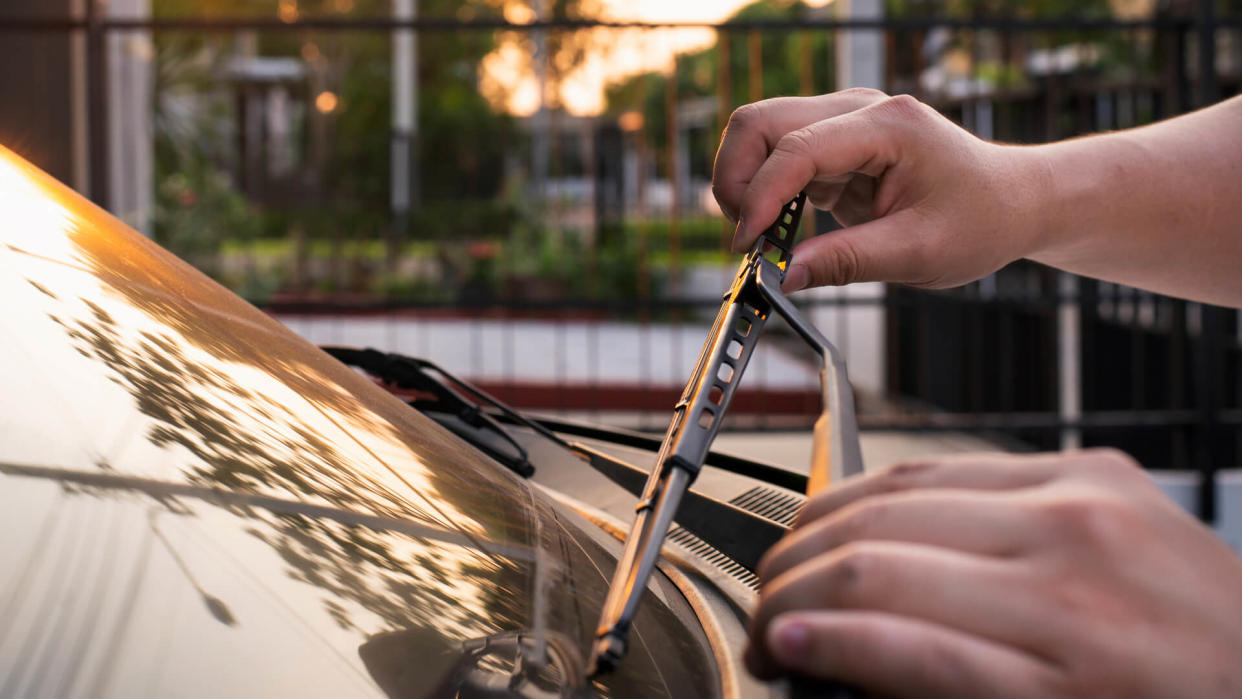 Technician is changing windscreen wipers on a car station,man hand picking up windscreen wiper or Mechanic check old wiper blade on sedan car.