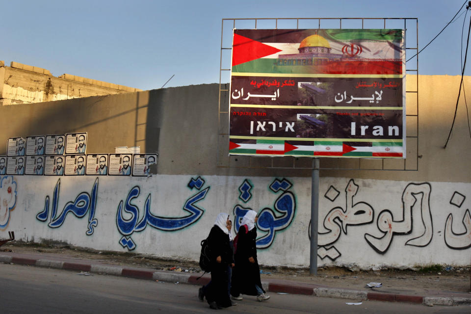 FILE - In this Nov. 28, 2012 file photo, Palestinian school girls pass a billboard covered by Palestinian and Iranian flags with Arabic that reads, "thanks and gratitude to Iran," in Gaza City. The Islamic Jihad group was founded in 1981 with the aim of establishing an Islamic Palestinian state in the West Bank, Gaza and all of what is now Israel. It is designated a terrorist organization by the U.S. State Department, European Union and other governments. Iran supplies Islamic Jihad with training, expertise and money, but most of the group's weapons are locally produced. (AP Photo/Adel Hana, File)