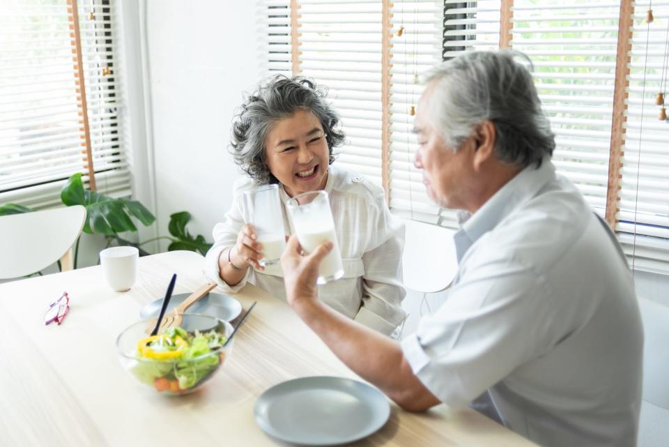 Adults holding glasses of milk together at home.