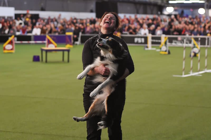 A woman celebrates with her dog after participating in the Masters Agility Championship during the Westminster Kennel Club Dog Show in New York