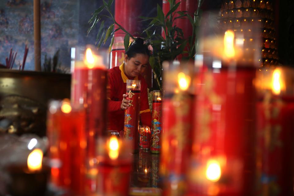 A woman holds a candle during Lunar New Year celebration at Satya Dharma temple in Denpasar, Bali, Indonesia on Saturday, Feb. 10, 2024. Chinese around the globe are celebrating the Lunar New Year that marks of the dragon on the Chinese calendar this year.