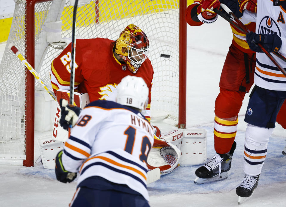 Edmonton Oilers left wing Zach Hyman, front left, scores on Calgary Flames goalie Jacob Markstrom during the second period of Game 1 of an NHL hockey second-round playoff series Wednesday, May 18, 2022, in Calgary, Alberta. (Jeff McIntosh/The Canadian Press via AP)