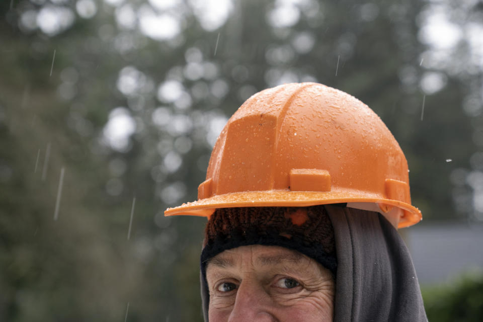 Mark Bourgeois, owner of ArborPro, watches his crew remove a tree on Tuesday, Jan. 16, 2024, in Lake Oswego, Ore., as freezing rain falls. (AP Photo/Jenny Kane)