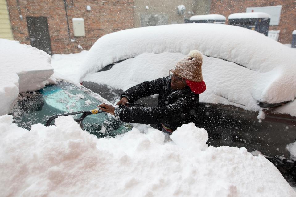 Zaria Black, 24, from Buffalo, clears off her car as snow falls Friday, Nov. 18, 2022, in Buffalo, N.Y.  A dangerous lake-effect snowstorm paralyzed parts of western and northern New York, with nearly 2 feet of snow already on the ground in some places and possibly much more on the way.  (AP Photo/Joshua Bessex)