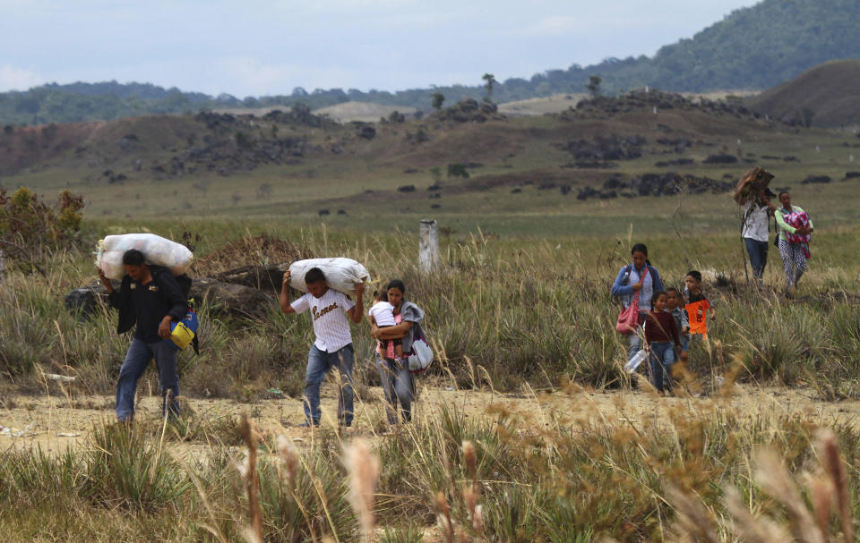 Venezuelans walk into Brazil through a field, in Pacaraima, Roraima state, Brazil, Friday, Feb.22, 2019. Venezuela's President Nicolas Maduro ordered the border closed as the opposition made plans to bring in humanitarian aid from Brazil and two other neighboring countries on Saturday. (AP Photo/Edmar Barros)