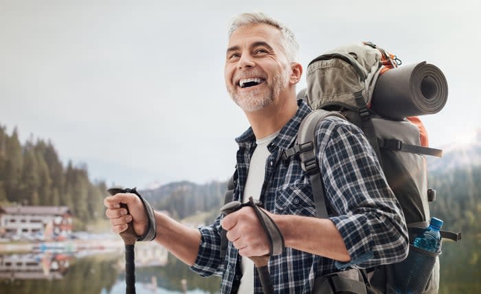 Someone is outdoors hiking with walking sticks and smiling.