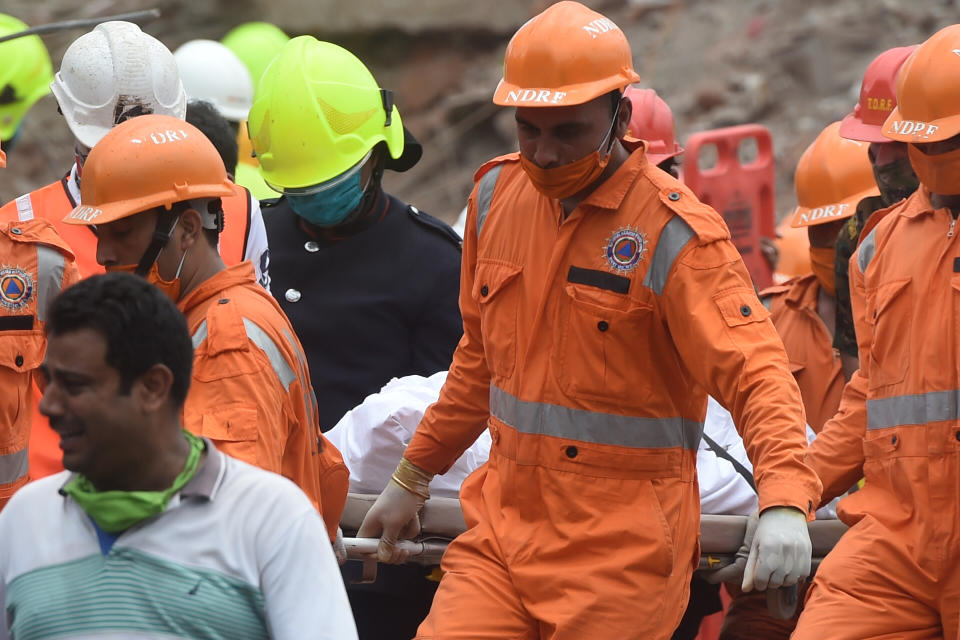 Rescue workers carry the body of a victim who died after a five-storey apartment building collapsed in Mahad. (Photo by PUNIT PARANJPE/AFP via Getty Images)