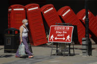 FILE - In this Monday, June 22, 2020 file photo, a sign requests people to stay two meters apart to reduce the spread of COVID-19 is displayed in front of "Out of Order" a 1989 red phone box sculpture by British artist David Mach, in London. So far in the vaccine race UK vaccination stats have a rate of 15 percent compared to some 3 percent in the EU bloc. The EU has already lost some 480,000 citizens to the pandemic in a bloc of 450 million with more fatalities mounting by the day. (AP Photo/Matt Dunham, File)