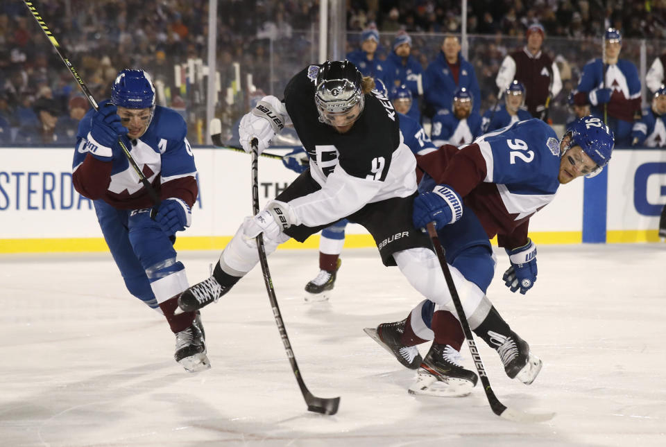 Los Angeles Kings center Adrian Kempe, center, shoots the puck as Colorado Avalanche defenseman Erik Johnson, left, and left wing Gabriel Landeskog defend during the first period of an NHL hockey game Saturday, Feb. 15, 2020, at Air Force Academy, Colo. (AP Photo/David Zalubowski)