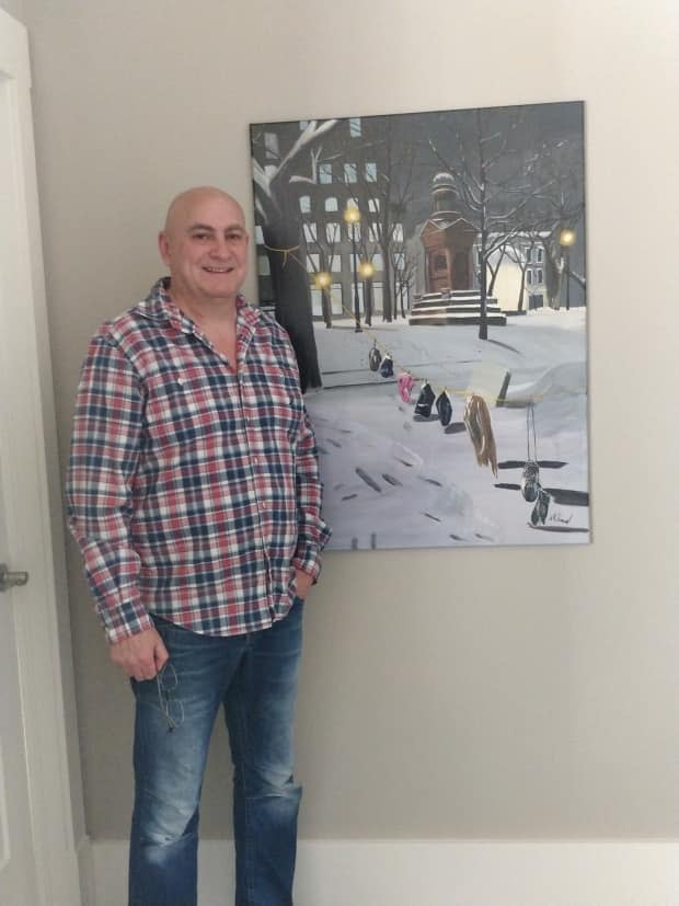 Norman Simard stands next to his painting titled Mittens. Simard started painting when the pandemic was declared, and a year later, two of his pieces made it into an international exhibit.  (Submitted by Norman Simard - image credit)