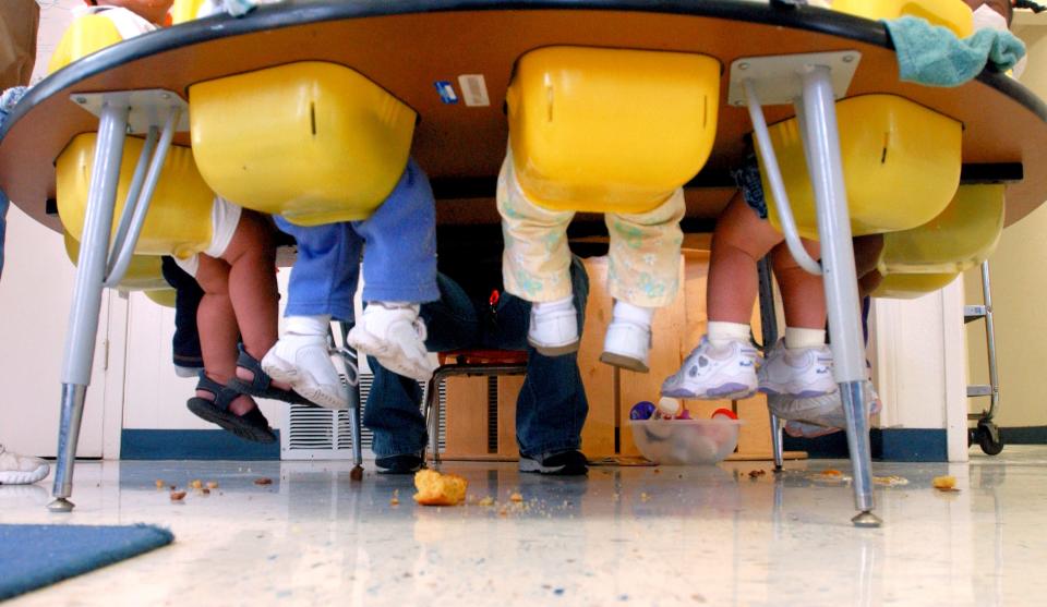 Toddlers' feet dangle in the air during lunch at the Cedar Street Day Nursery 20 years ago.