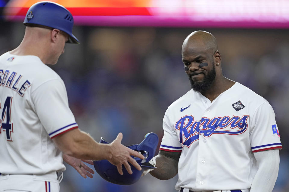 Texas Rangers' Adolis Garcia, right, hands his helmet to first base coach Corey Ragsdale after flying out to end the fourth inning in Game 2 of the baseball World Series against the Arizona Diamondbacks Saturday, Oct. 28, 2023, in Arlington, Texas. (AP Photo/Godofredo A. Vásquez)