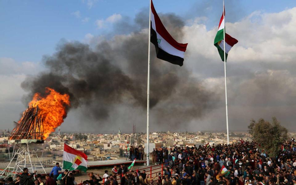 <p>The Kurdish and Iraqi flag sway in the wind as a bonfire burns during the Noruz spring festival celebrations in the northern city of Kirkuk, about 150 miles north of Baghdad.</p>