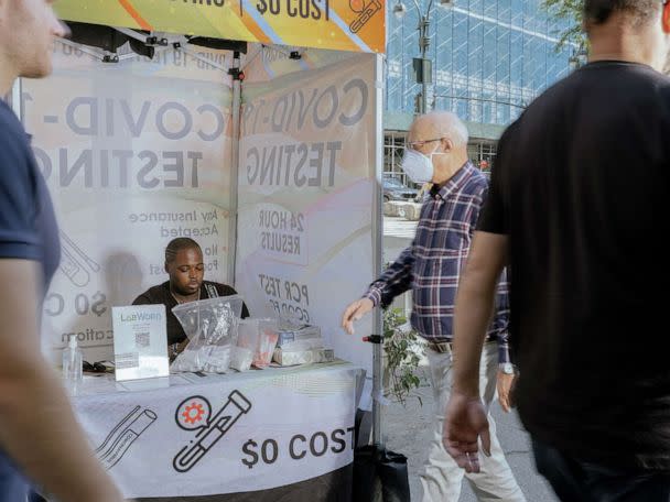 PHOTO: People walk past a mobile COVID-19 testing site in New York City, May 22, 2022. (Bloomberg via Getty Images)