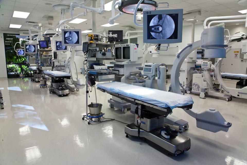 Suite of surgical tables with sophisticated equipment surrounding them, including monitors, lighting, and instrumentation.